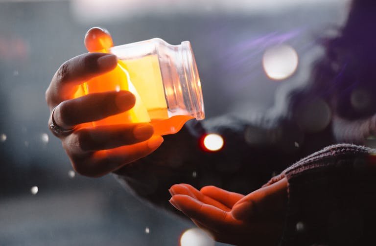 A hand holding a glowing jar, creating a warm and cozy night atmosphere indoors.