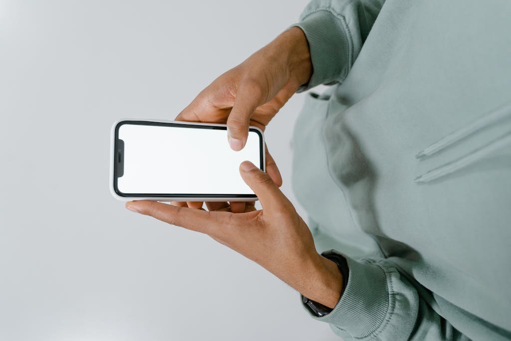 Hands holding a smartphone with a blank screen, perfect for mockups and copy space.